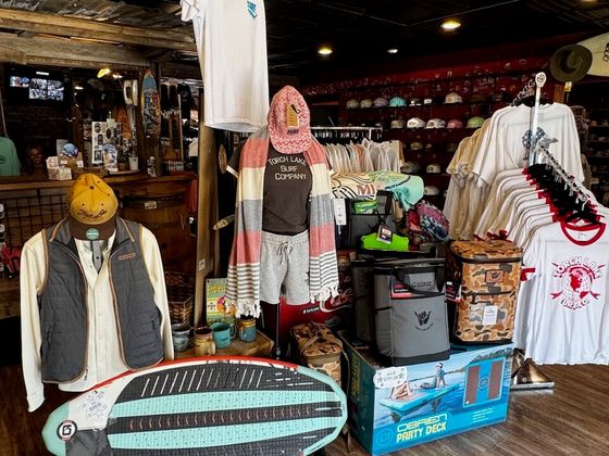 A wakesurf board propped in front of a display of soft coolers and an O’Brien Party Deck box