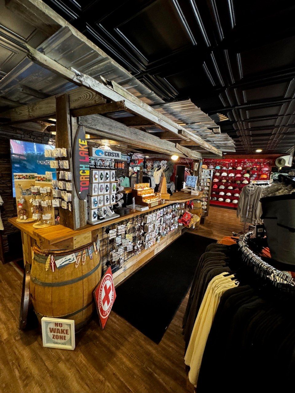 The same register counter from a step to the right, racks of black and cream apparel filling the foreground