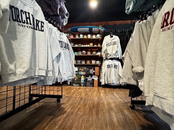 Racks of heather-grey crewnecks and hoodies reading TORCH LAKE SURF COMPANY in block letters